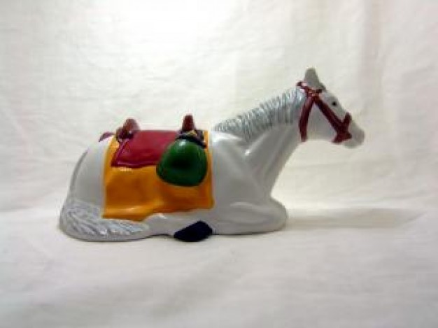 ceramic horse toy siiting with orange sadlle